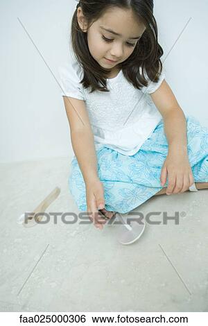 Girl sitting on the ground playing with top, close-up View Large Photo Image Stock Photograph - Girl sitting on the ground playing with top, close-up. Fotosearch