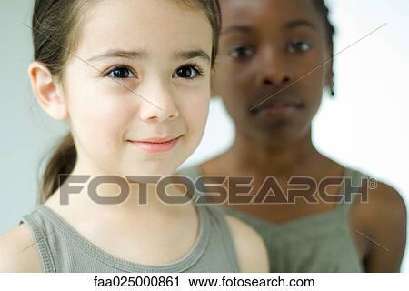 Girl smiling and looking away, friend in background looking at camera View Large Photo Image Stock Image - Girl smiling and looking away, friend in background looking at camera. Fotosearch