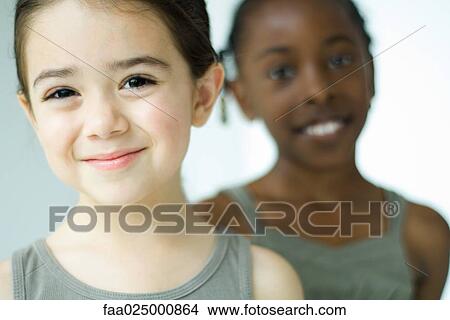 Girl smiling at camera, friend in background View Large Photo Image Picture - Girl smiling at camera, friend in background. Fotosearch