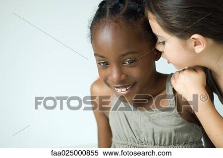 Girl whispering in friends ear, cropped view View Large Photo Image Stock Photography - Girl whispering in friends ear, cropped view. Fotosearch