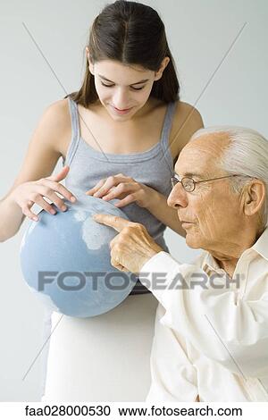 Stock Image - Grandfather and granddaughter looking at globe together. Fotosearch