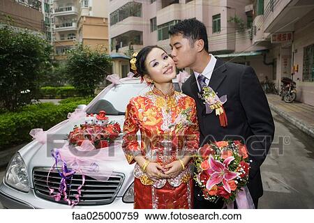 Groom kissing bride on cheek in front of car View Large Photo Image Stock Photo - Groom kissing bride on cheek in front of car. Fotosearch