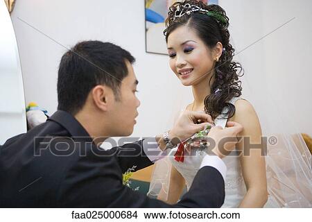 Groom pinning corsage on bride's dress View Large Photo Image Picture - Groom pinning corsage on bride's dress. Fotosearch