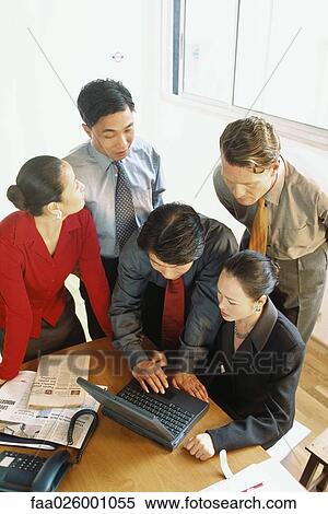Group of professionals looking down at laptop computer together, high angle view View Large Photo Image Stock Photography - Group of professionals looking down at laptop computer together, high angle view. Fotosearch