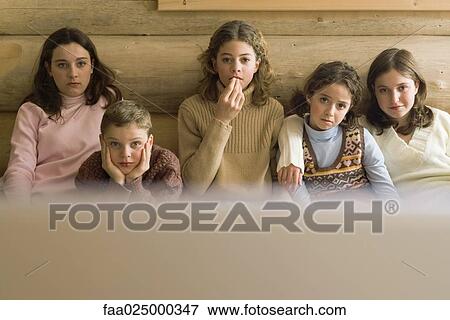 Group of teen and preteen friends and siblings watching TV, front view View Large Photo Image Stock Photo - Group of teen and preteen friends and siblings watching TV, front view. Fotosearch