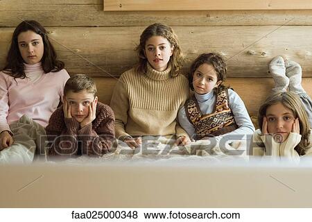 Group of teen and preteen friends and siblings watching TV, front view View Large Photo Image Stock Photo - Group of teen and preteen friends and siblings watching TV, front view. Fotosearch