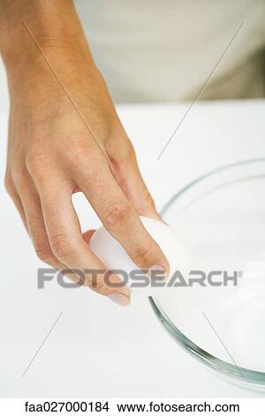 Hand cracking egg against side of bowl, cropped view, close-up View Large Photo Image Picture - Hand cracking egg against side of bowl, cropped view, close-up. Fotosearch