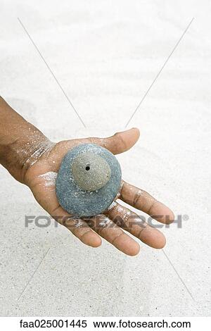 Stock Photography - Hand holding stacked pebbles, close-up. Fotosearch