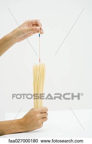 Hands holding dried pasta, measuring with stick View Large Photo Image Stock Image - Hands holding dried pasta, measuring with stick. Fotosearch
