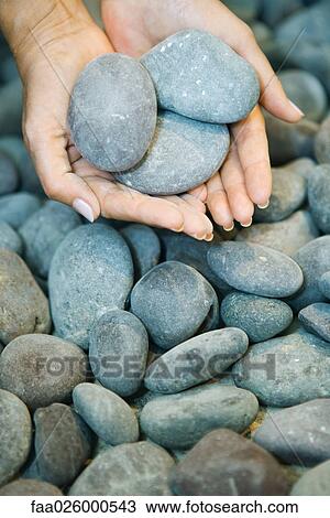 Stock Image - Hands holding pebbles, close-up. Fotosearch