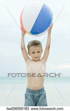 Little boy at the beach, holding up beach ball, smiling at camera View Large Photo Image Stock Image - Little boy at the beach, holding up beach ball, smiling at camera. Fotosearch