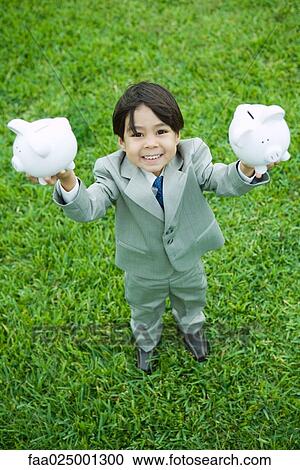Little boy dressed in full suit holding up piggy banks View Large Photo Image Stock Image - Little boy dressed in full suit holding up piggy banks. Fotosearch
