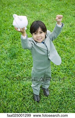 Little boy dressed in full suit holding up piggy bank View Large Photo Image Stock Photo - Little boy dressed in full suit holding up piggy bank. Fotosearch