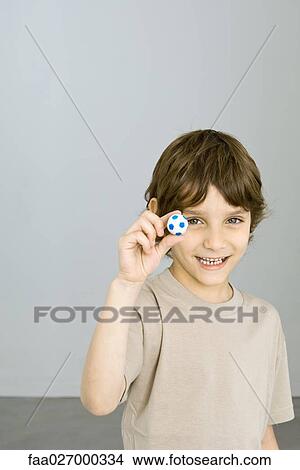 Little boy holding up miniature soccer ball, smiling at camera View Large Photo Image Picture - Little boy holding up miniature soccer ball, smiling at camera. Fotosearch