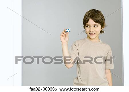 Little boy holding up miniature soccer ball, smiling View Large Photo Image Stock Photography - Little boy holding up miniature soccer ball, smiling. Fotosearch