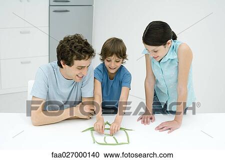 Little boy in kitchen with father and sister, building house out of green beans, all smiling View Large Photo Image Stock Image - Little boy in kitchen with father and sister, building house out of green beans, all smiling. Fotosearch