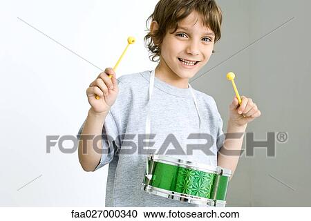 Stock Image - Little boy playing drum, smiling at camera. Fotosearch