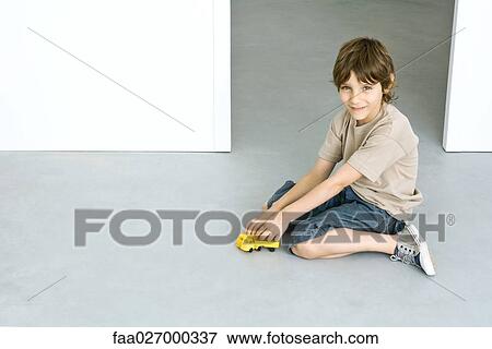 Little boy sitting on the ground, playing with toy truck, smiling at camera View Large Photo Image Stock Photo - Little boy sitting on the ground, playing with toy truck, smiling at camera. Fotosearch