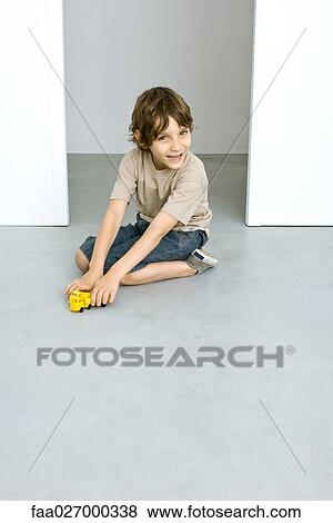 Little boy sitting on the ground, playing with toy trucks, smiling at camera View Large Photo Image Stock Photo - Little boy sitting on the ground, playing with toy trucks, smiling at camera. Fotosearch