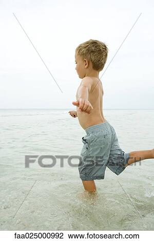 Little boy standing in shallow water, posed to kick View Large Photo Image Stock Image - Little boy standing in shallow water, posed to kick. Fotosearch
