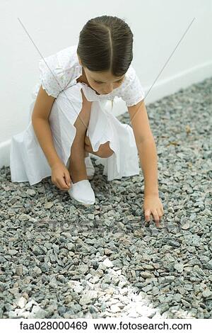 Little girl crouching, picking up gravel, head down View Large Photo Image Stock Photo - Little girl crouching, picking up gravel, head down. Fotosearch