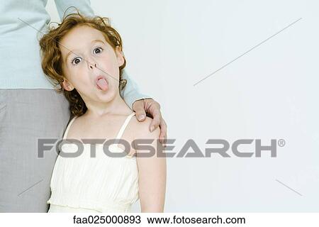 Little girl holding onto mother's leg, sticking tongue out at camera View Large Photo Image Stock Image - Little girl holding onto mother's leg, sticking tongue out at camera. Fotosearch