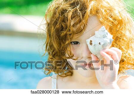 Little girl holding seashell in front of face, looking at camera View Large Photo Image Stock Photo - Little girl holding seashell in front of face, looking at camera. Fotosearch