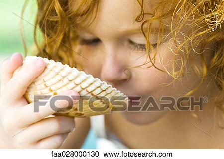 Little girl holding seashell up to face, close-up View Large Photo Image Stock Image - Little girl holding seashell up to face, close-up. Fotosearch