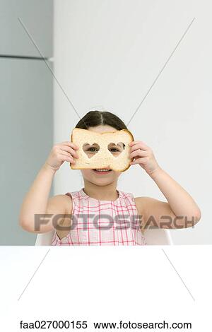 Little girl holding up bread with heart shaped cut outs, looking through holes at camera View Large Photo Image Stock Photography - Little girl holding up bread with heart shaped cut outs, looking through holes at camera. Fotosearch