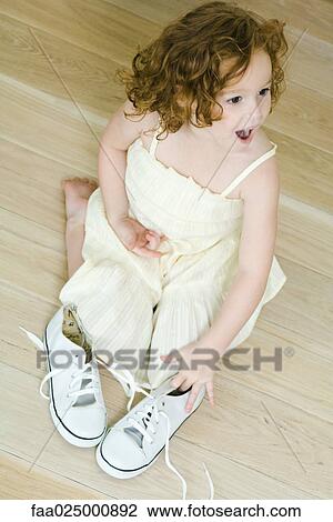 Little girl kneeling on ground near pair of shoes, looking surprised View Large Photo Image Stock Image - Little girl kneeling on ground near pair of shoes, looking surprised. Fotosearch