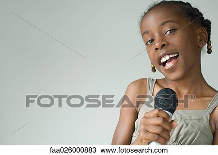 Little girl singing into microphone, smiling at camera, close-up View Large Photo Image Stock Image - Little girl singing into microphone, smiling at camera, close-up. Fotosearch