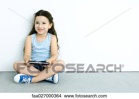 Little girl sitting on the ground, playing handheld video game, smiling View Large Photo Image Picture - Little girl sitting on the ground, playing handheld video game, smiling. Fotosearch