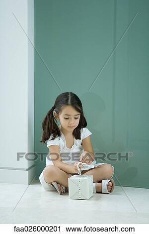 Little girl sitting on the ground, tying ribbon on gift View Large Photo Image Stock Image - Little girl sitting on the ground, tying ribbon on gift. Fotosearch