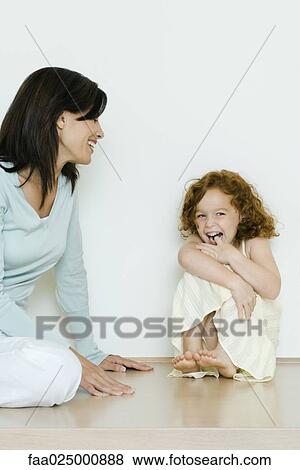 Little girl sitting with mother, giggling View Large Photo Image Stock Photo - Little girl sitting with mother, giggling. Fotosearch