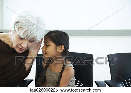 Stock Photography - Little girl whispering in grandmother's ear, both looking away. Fotosearch