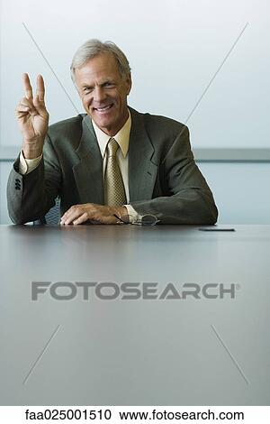 Stock Image - looking at camera, gesture, smiling, leaning on elbow, businessman, ceo. Fotosearch