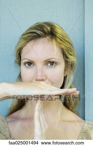 Picture - looking at camera, hand, woman, time out signal, young women, communication, time. Fotosearch