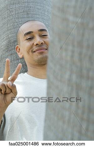 looking at camera, smiling, tree trunk, peace sign, mid adult men, peace View Large Photo Image Stock Photograph - looking at camera, smiling, tree trunk, peace sign, mid adult men, peace. Fotosearch