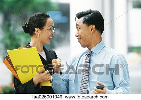 Stock Photo - Male and female business partners smiling at each other, man clenching fist. Fotosearch