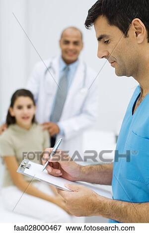 Male nurse writing on clipboard, young patient and doctor in background View Large Photo Image Stock Photo - Male nurse writing on clipboard, young patient and doctor in background. Fotosearch