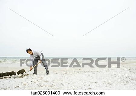 Man at the beach, bending over and digging in sand, smiling at camera View Large Photo Image Stock Image - Man at the beach, bending over and digging in sand, smiling at camera. Fotosearch