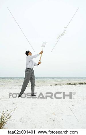 Man at the beach holding up shovel, throwing sand, full length View Large Photo Image Stock Image - Man at the beach holding up shovel, throwing sand, full length. Fotosearch