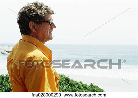 Man at the beach, looking at view, side view View Large Photo Image Stock Image - Man at the beach, looking at view, side view. Fotosearch