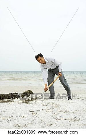 Man at the beach scooping sand with shovel, smiling at camera, full length View Large Photo Image Stock Photo - Man at the beach scooping sand with shovel, smiling at camera, full length. Fotosearch