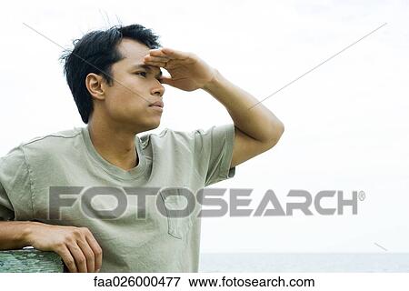 Man at the beach shading eyes, looking away, close-up View Large Photo Image Stock Photo - Man at the beach shading eyes, looking away, close-up. Fotosearch