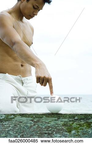 Man at the beach touching ball with forefinger, low angle view View Large Photo Image Stock Photography - Man at the beach touching ball with forefinger, low angle view. Fotosearch