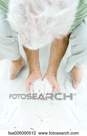 Man bending over, holding sand in both hands, high angle view View Large Photo Image Stock Image - Man bending over, holding sand in both hands, high angle view. Fotosearch