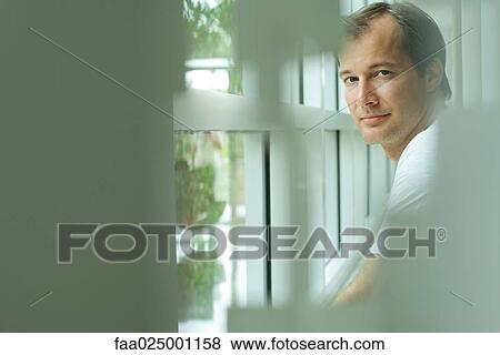 Man by window, looking at camera, selective focus View Large Photo Image Stock Photo - Man by window, looking at camera, selective focus. Fotosearch