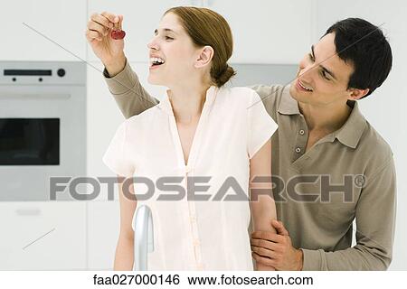 Man feeding woman cherry, both smiling, looking away View Large Photo Image Stock Photograph - Man feeding woman cherry, both smiling, looking away. Fotosearch