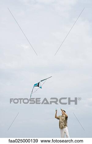 Man flying kite, looking up View Large Photo Image Stock Photo - Man flying kite, looking up. Fotosearch